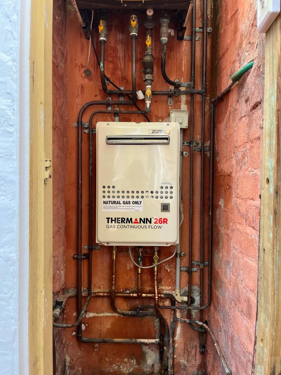 Thermann gas continuous-flow hot water unit installed on a brick wall